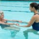 Terapia ocupacional medio acuático, mujer mayor entrenando con pesas en la piscina
